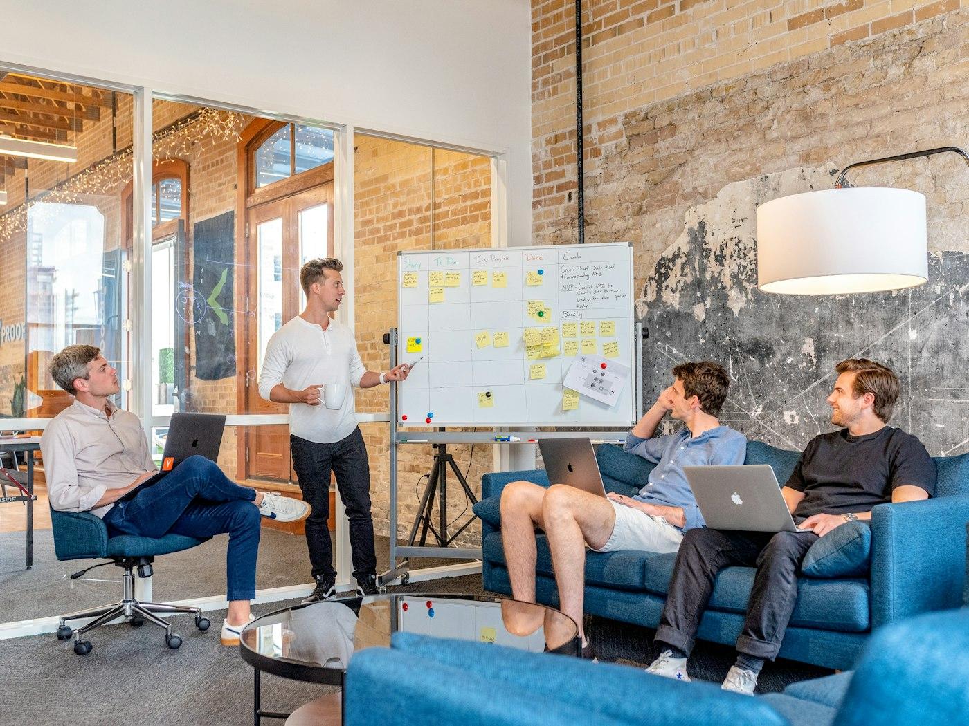 Formateur accompagnant un petit groupe autour d'un tableau blanc, dans un bureau lumineux